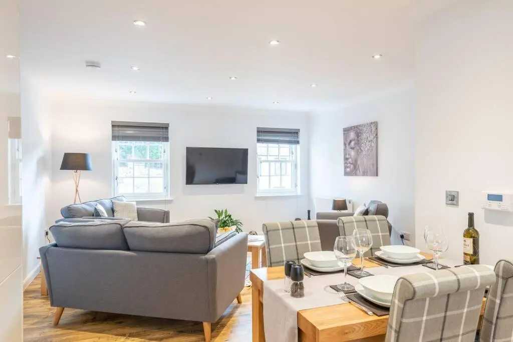 a living room with a table and couches and a television at Stylish & Modern Apartment in Inverness