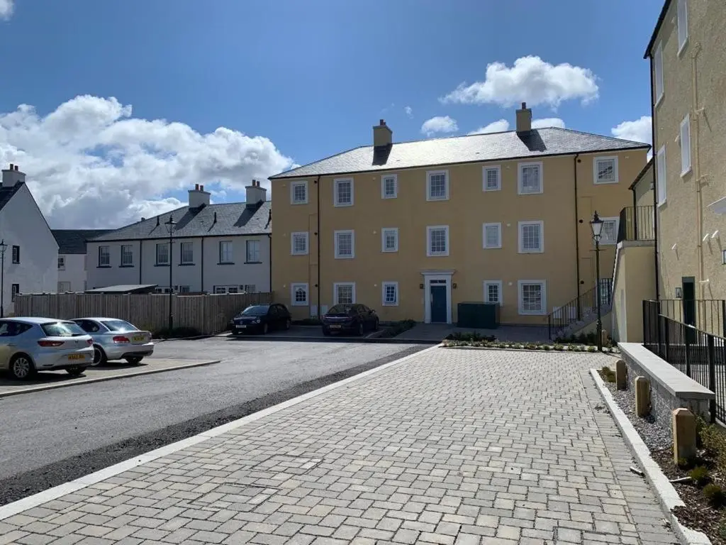 a yellow building with cars parked in a parking lot at Stylish & Modern Apartment in Inverness