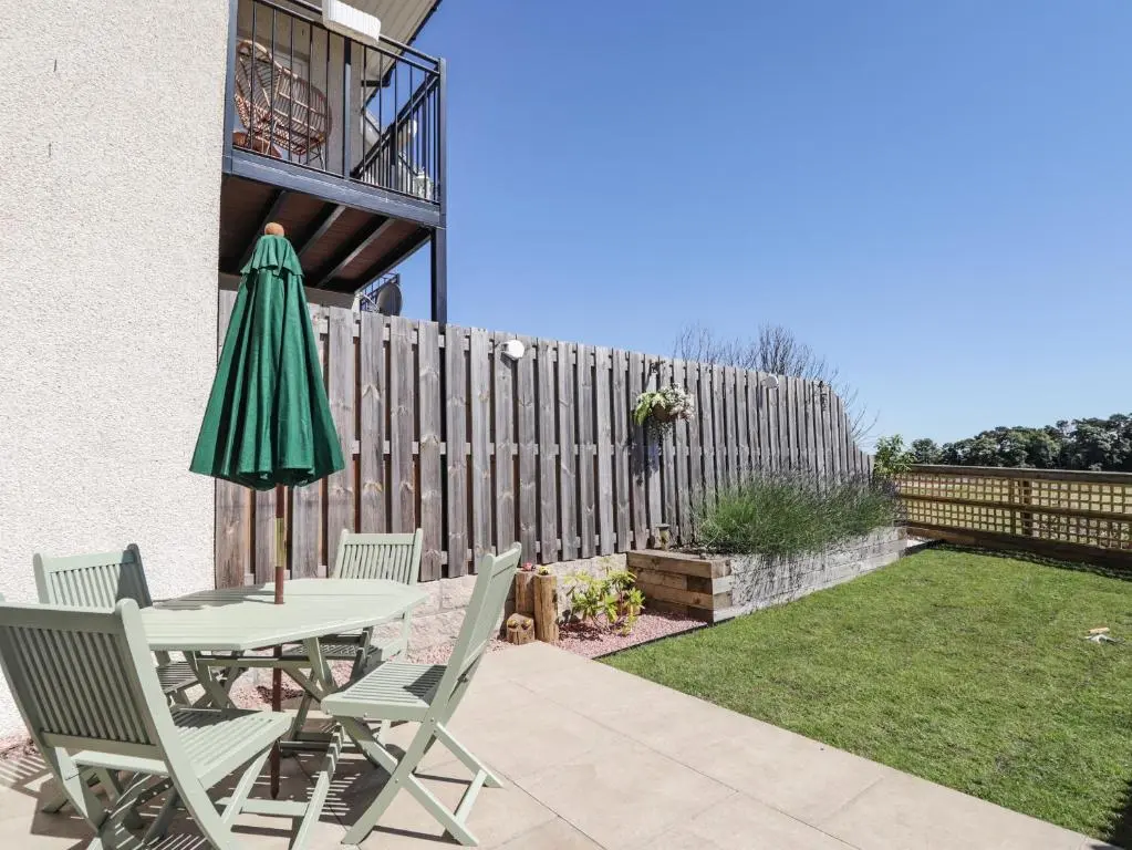 a patio with a table and chairs and an umbrella at 38 The Views in Elgin