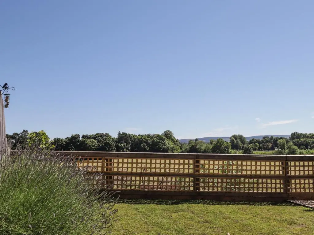 a wooden fence in a yard with trees in the background at 38 The Views in Elgin