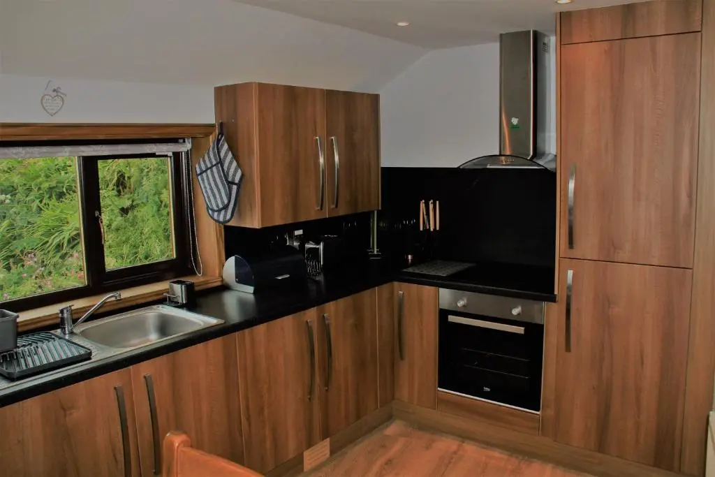 a kitchen with wooden cabinets and a sink and a window at Bellevue Holiday Cottage in Gardenstown