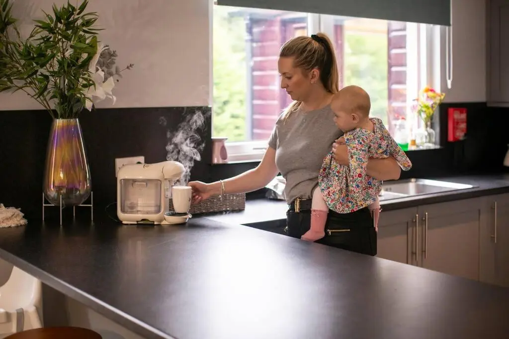 a woman holding a baby in a kitchen at Calm Scottish Country Escape with Hot Tub Sleeps 6 in Inverness