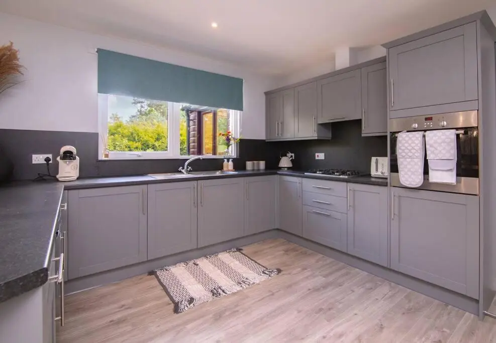 a large kitchen with white cabinets and a window at Calm Scottish Country Escape with Hot Tub Sleeps 6 in Inverness