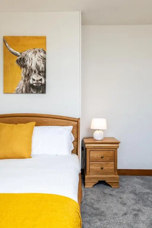 a bedroom with a bed and a picture of a cow at Stunning, Remodelled Cottage, Picturesque Location in Duncanston