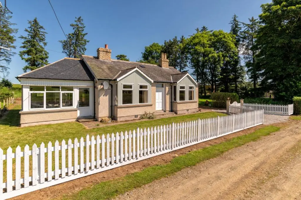 a white picket fence in front of a house at Stunning, Remodelled Cottage, Picturesque Location in Duncanston