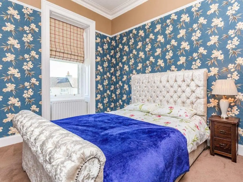 a bedroom with a bed with blue floral wallpaper at North Bank House in Lybster