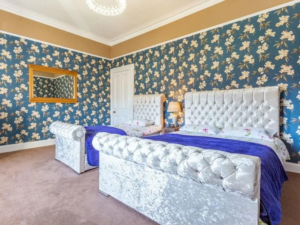 a bedroom with a bed with blue and gold wallpaper at North Bank House in Lybster
