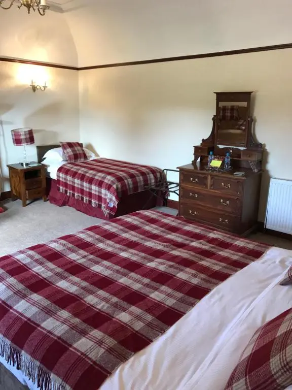 a hotel room with two beds and a dresser at Cavell House in Inverness