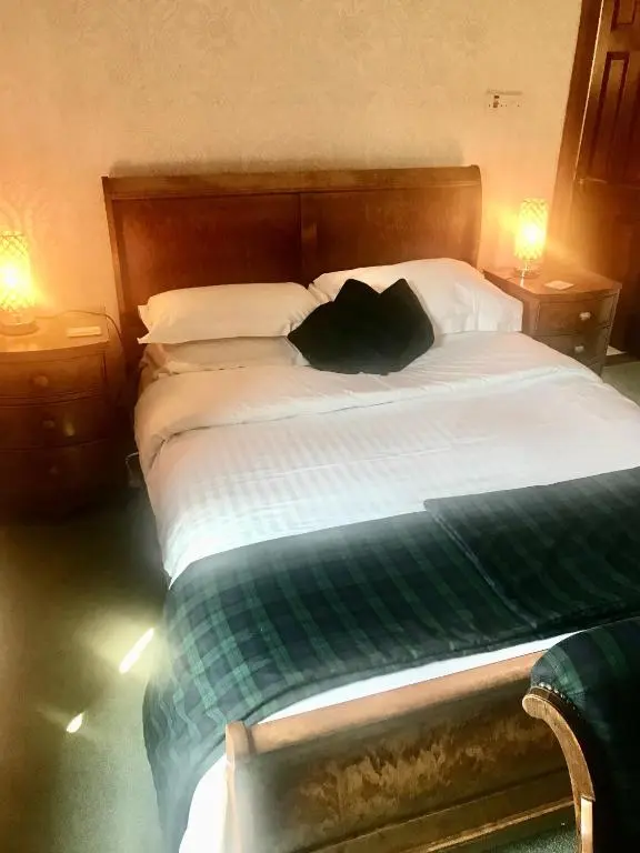 a large bed with a green and white comforter at Cavell House in Inverness