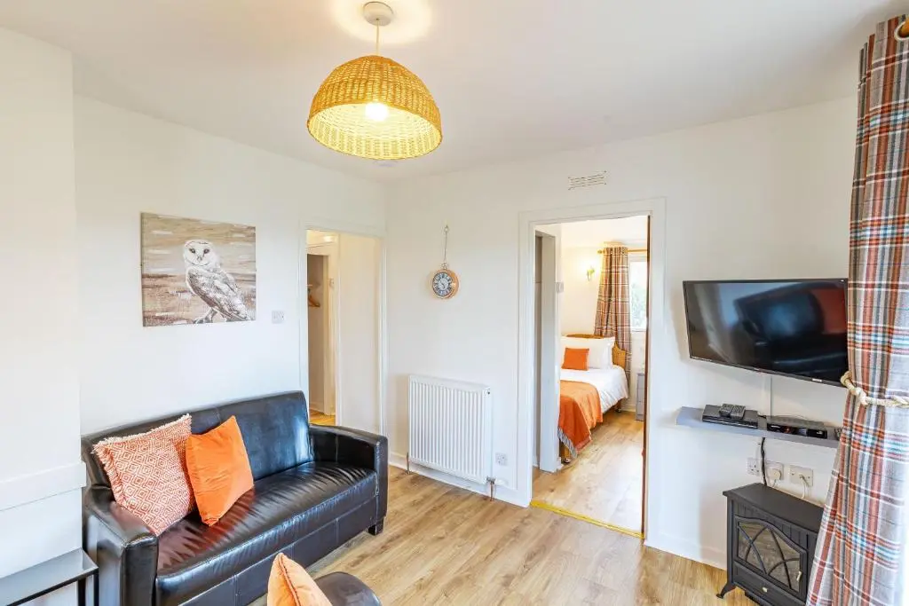 a living room with a couch and a television at Fern Lodge 2 with Hot Tub in Belladrum