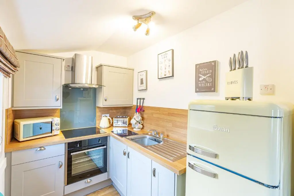 a kitchen with a refrigerator and a sink at Fern Lodge 2 with Hot Tub in Belladrum