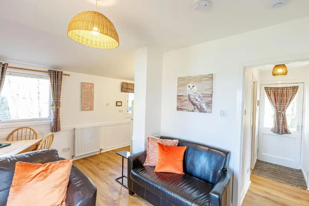 a living room with a leather couch and a table at Fern Lodge 2 with Hot Tub in Belladrum