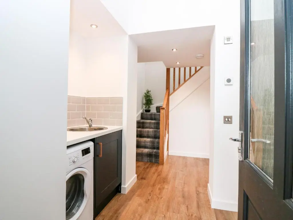 a laundry room with a sink and a washing machine at The Marriage Room at The Institute Executive Apartments in Keith