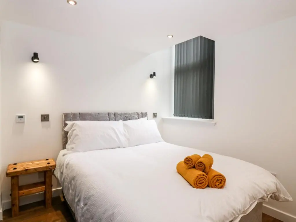 a bedroom with a bed with three towels on it at The Marriage Room at The Institute Executive Apartments in Keith