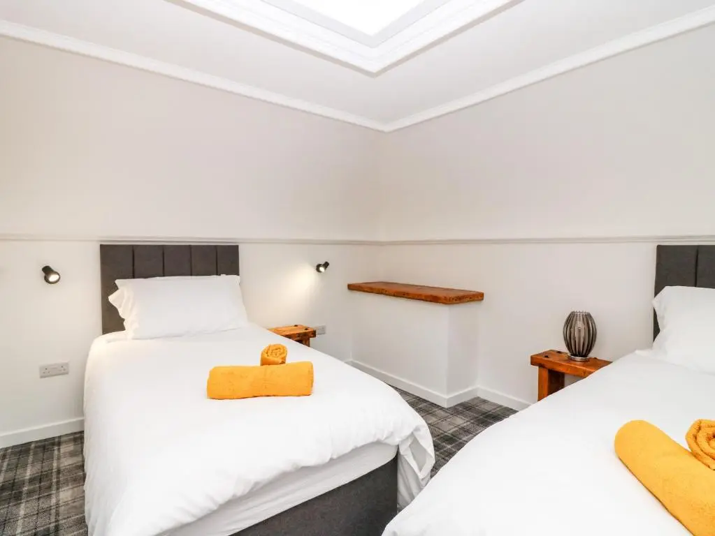 two beds in a room with white walls at The Marriage Room at The Institute Executive Apartments in Keith