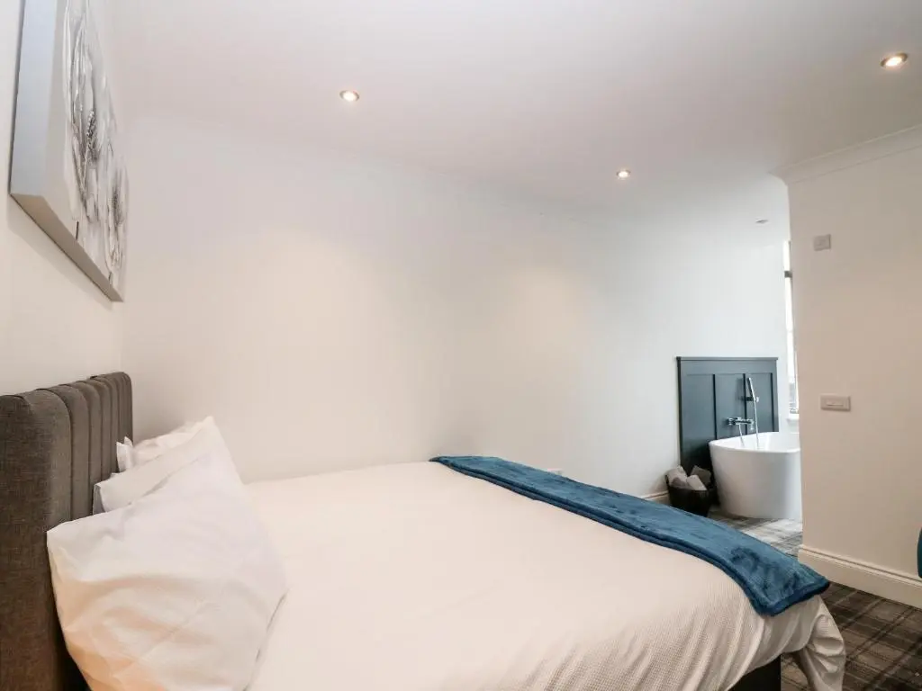 a white bedroom with a bed and a bath tub at The Clock Tower at The Institute Executive Apartments in Keith