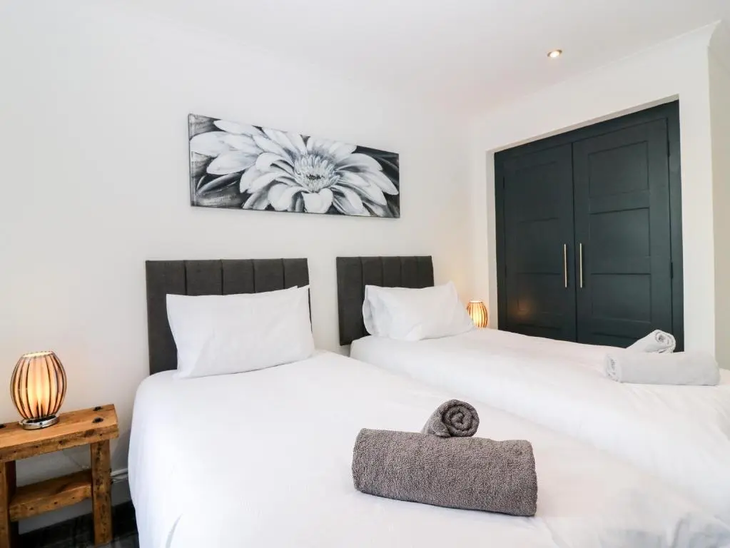 two beds in a room with white sheets at The Clock Tower at The Institute Executive Apartments in Keith