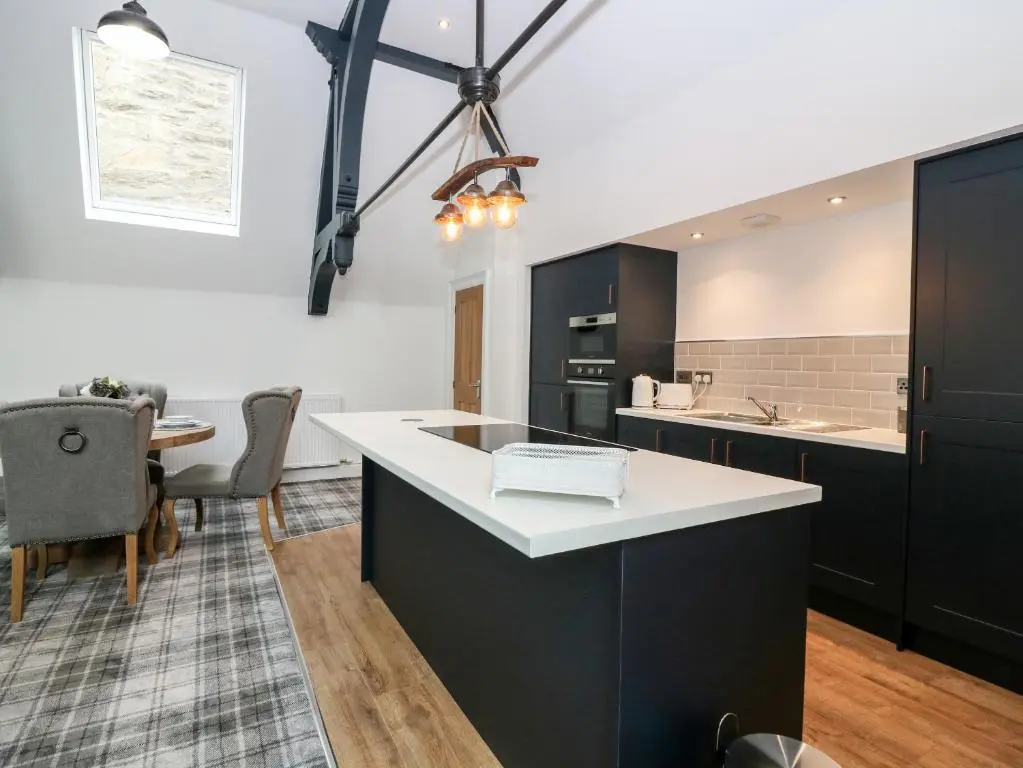 a kitchen with black cabinets and a white counter top at The Clock Tower at The Institute Executive Apartments in Keith