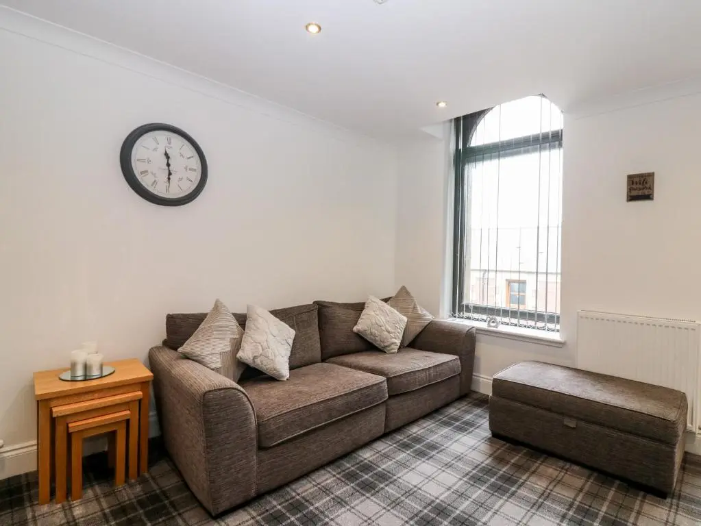 a living room with a couch and a clock on the wall at The Court Room at The Institute Executive Apartments in Keith