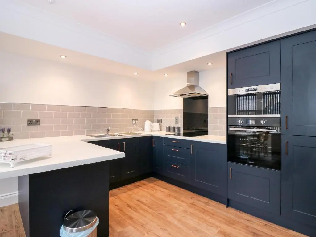 a kitchen with navy blue cabinets and white counter tops at The Court Room at The Institute Executive Apartments in Keith