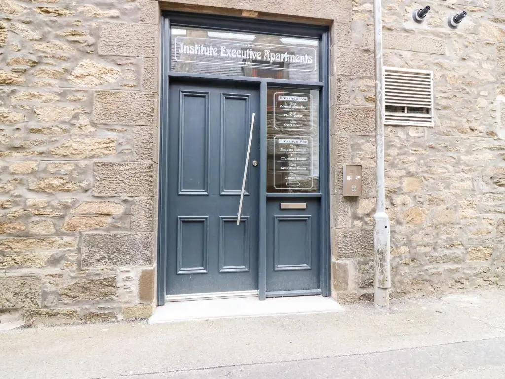 a blue door on a stone building with a sign above it at The Court Room at The Institute Executive Apartments in Keith