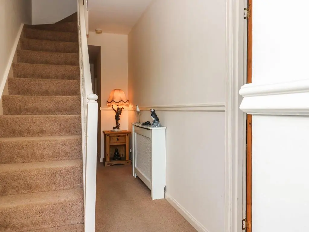 a hallway with stairs and a table and a lamp at Harbour View in Buckie