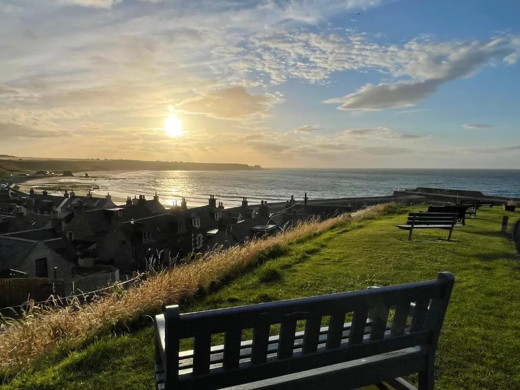 a group of benches sitting on the grass near the ocean at Spacious 2 Bedroom Home in Picturesque Cullen in Cullen