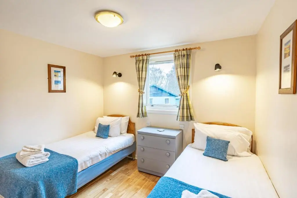 two twin beds in a room with a window at Bracken Lodge 5 with Hot Tub in Belladrum
