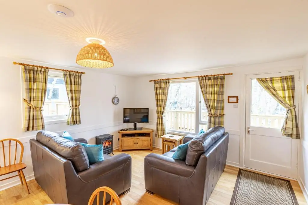 a living room with two leather chairs and a television at Bracken Lodge 5 with Hot Tub in Belladrum