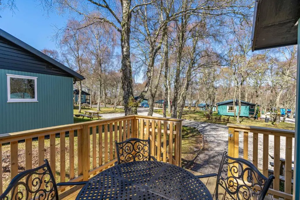 a patio with a table and chairs on a wooden deck at Bracken Lodge 5 with Hot Tub in Belladrum