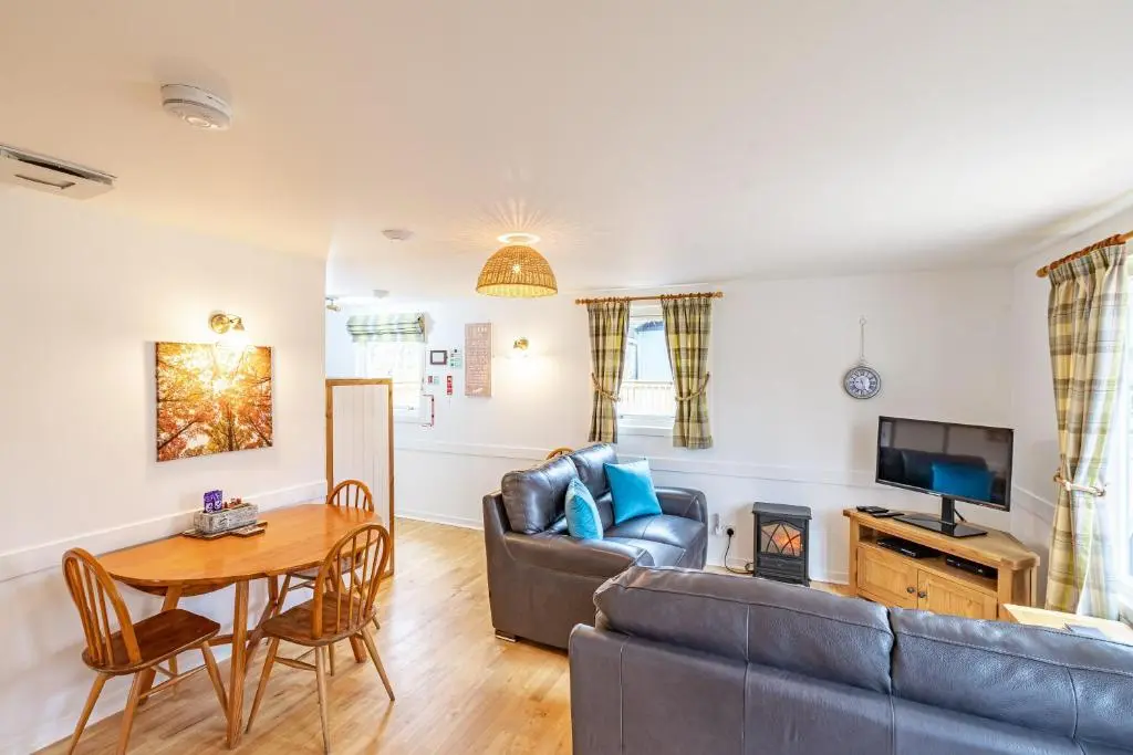 a living room with a couch and a table at Bracken Lodge 5 with Hot Tub in Belladrum