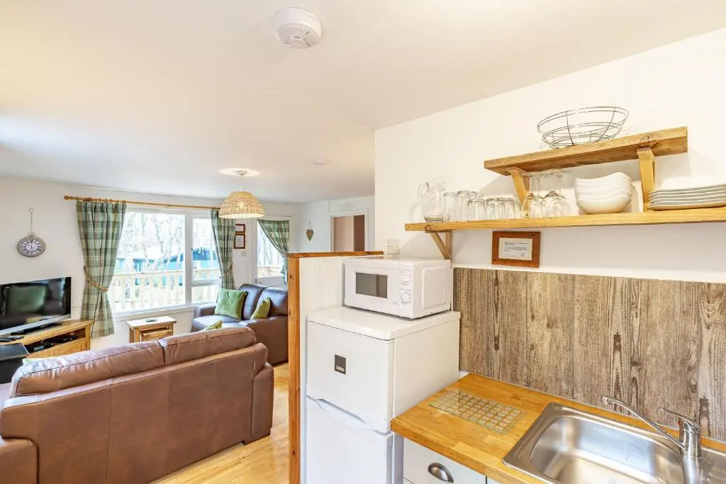 a kitchen and living room with a couch and a sink at Bracken Lodge 6 with Hot Tub in Belladrum