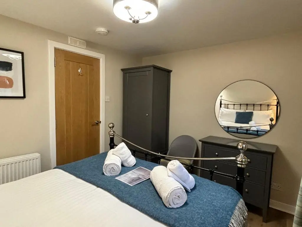a bedroom with a bed with a mirror and towels at Bracken Lodge 6 with Hot Tub in Belladrum