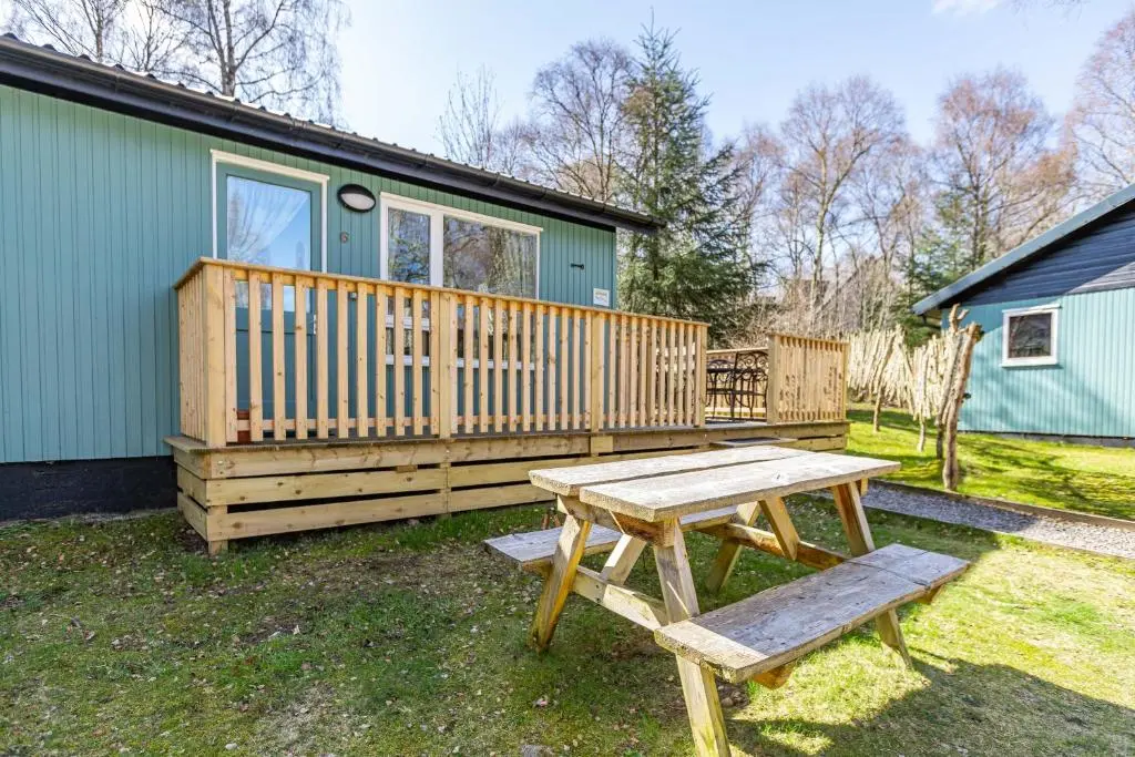 a picnic table and a bench in front of a house at Bracken Lodge 6 with Hot Tub in Belladrum