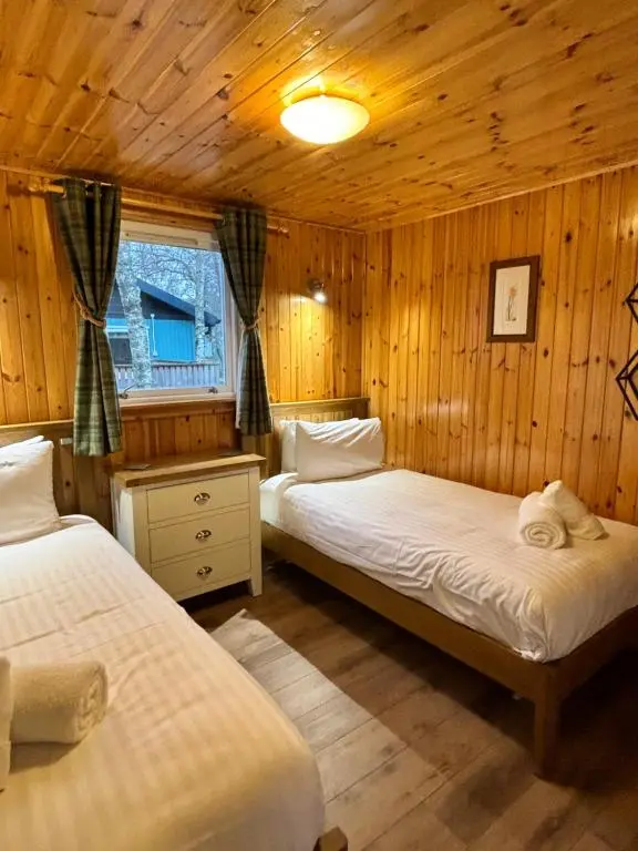 a bedroom with two beds in a wooden cabin at Bracken Lodge 6 with Hot Tub in Belladrum