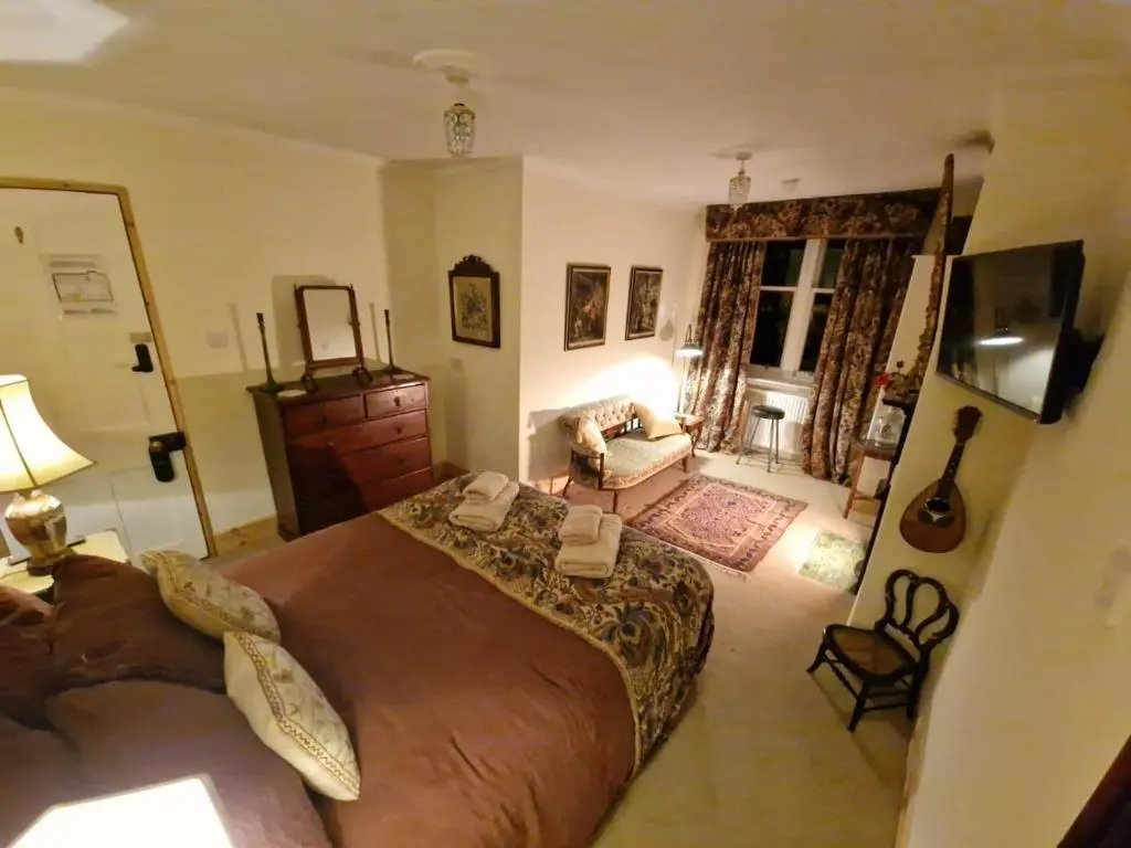 a bedroom with a large bed and a living room at Cambus O' May Traditional Highland Hotel in Ballater