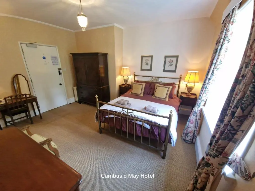 a bedroom with a bed and a table in a room at Cambus O' May Traditional Highland Hotel in Ballater