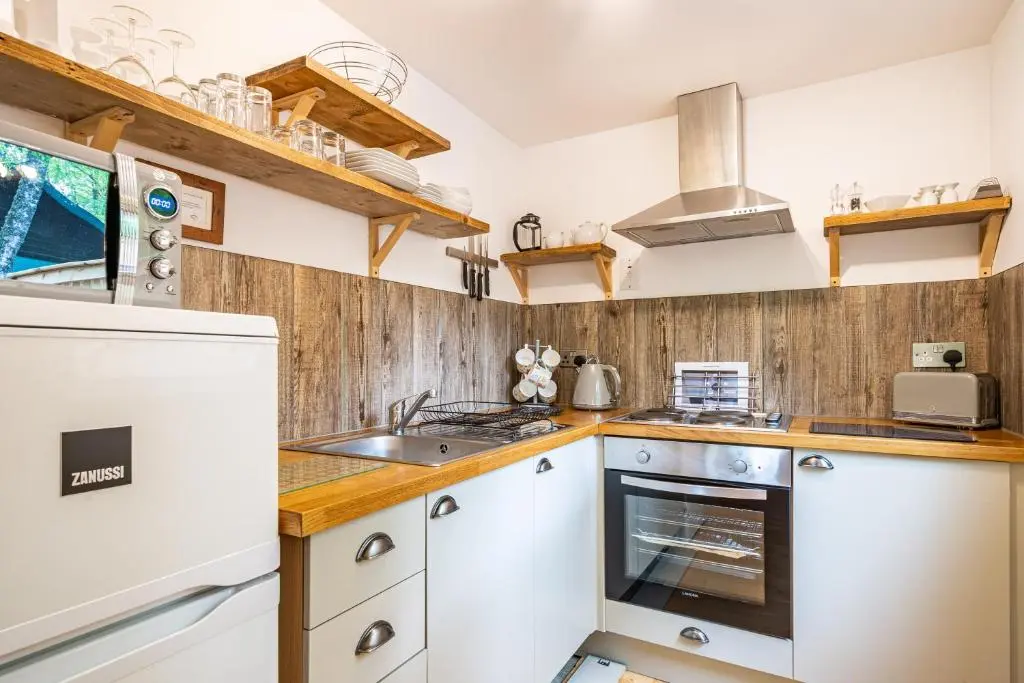 a kitchen with white appliances and wooden walls at Bracken Lodge 7 with Hot Tub in Belladrum