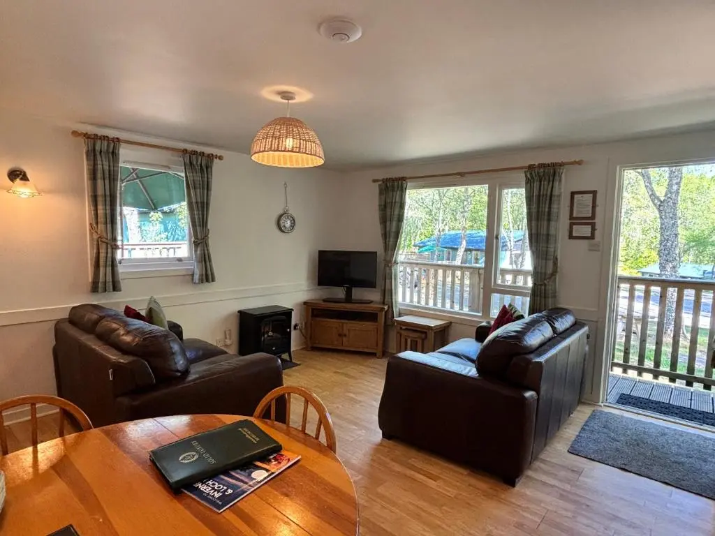 a living room with two couches and a table at Bracken Lodge 7 with Hot Tub in Belladrum