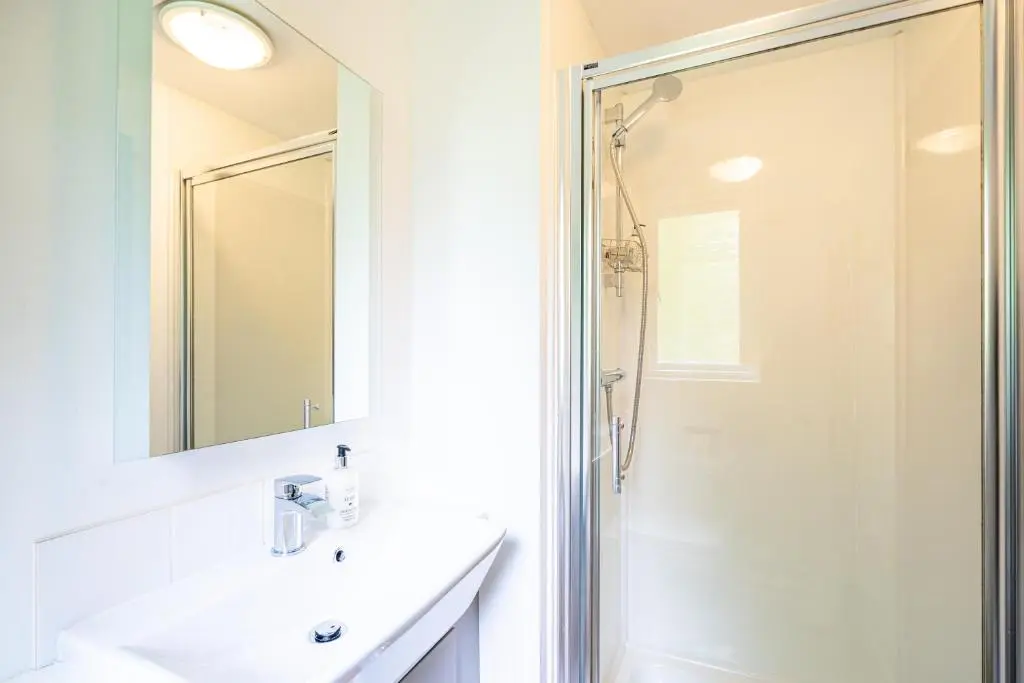 a bathroom with a shower and a sink and a mirror at Bracken Lodge 7 with Hot Tub in Belladrum