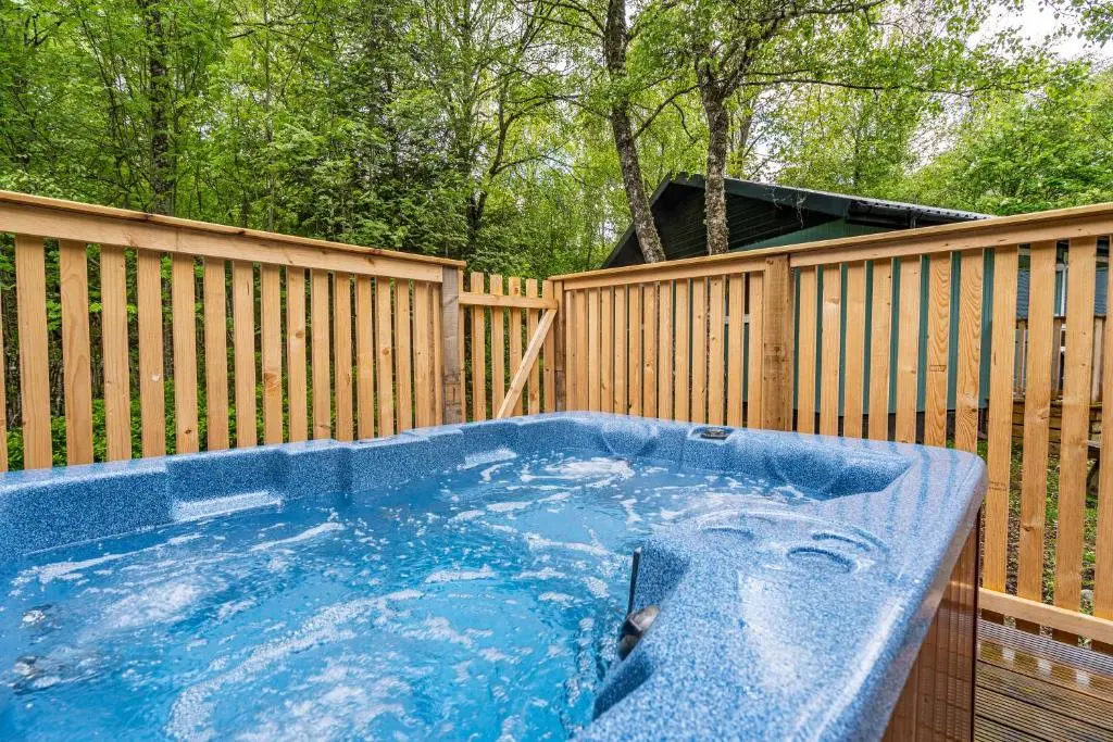 a hot tub in a backyard with a wooden fence at Bracken Lodge 7 with Hot Tub in Belladrum