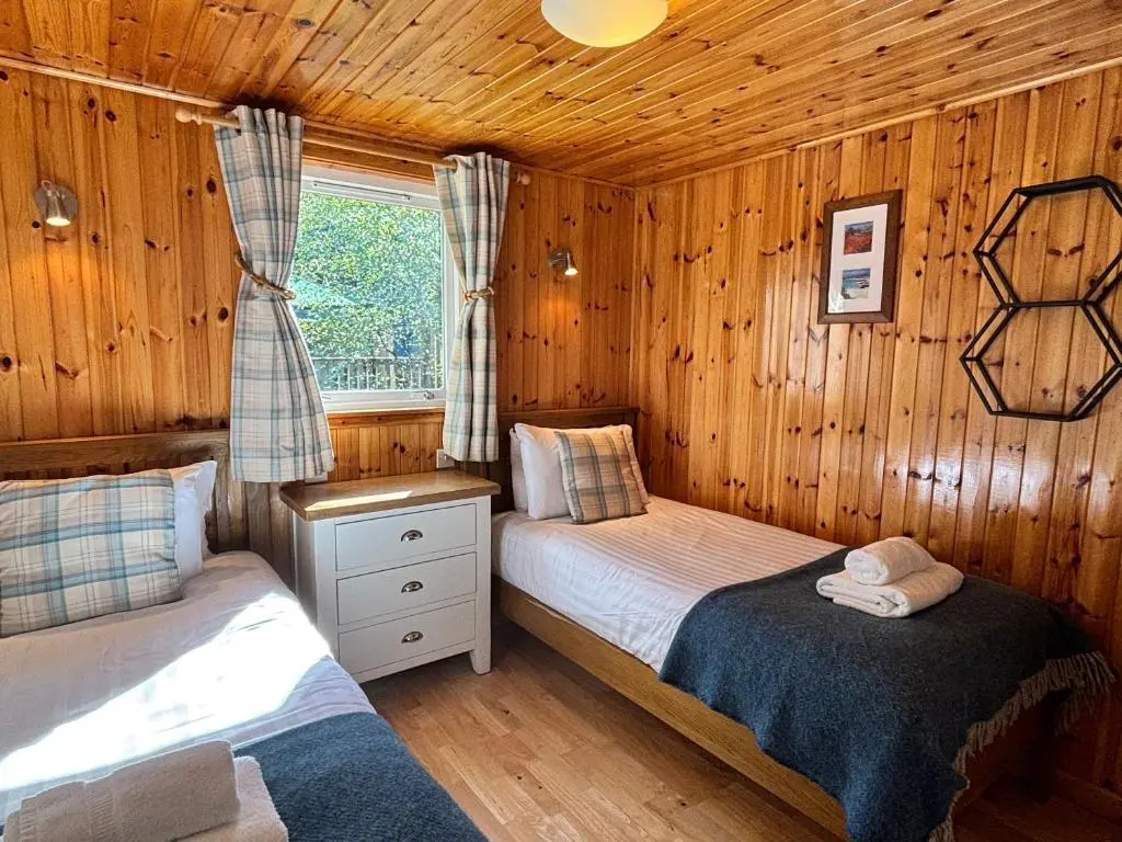 a bedroom with two beds in a wooden cabin at Bracken Lodge 7 with Hot Tub in Belladrum