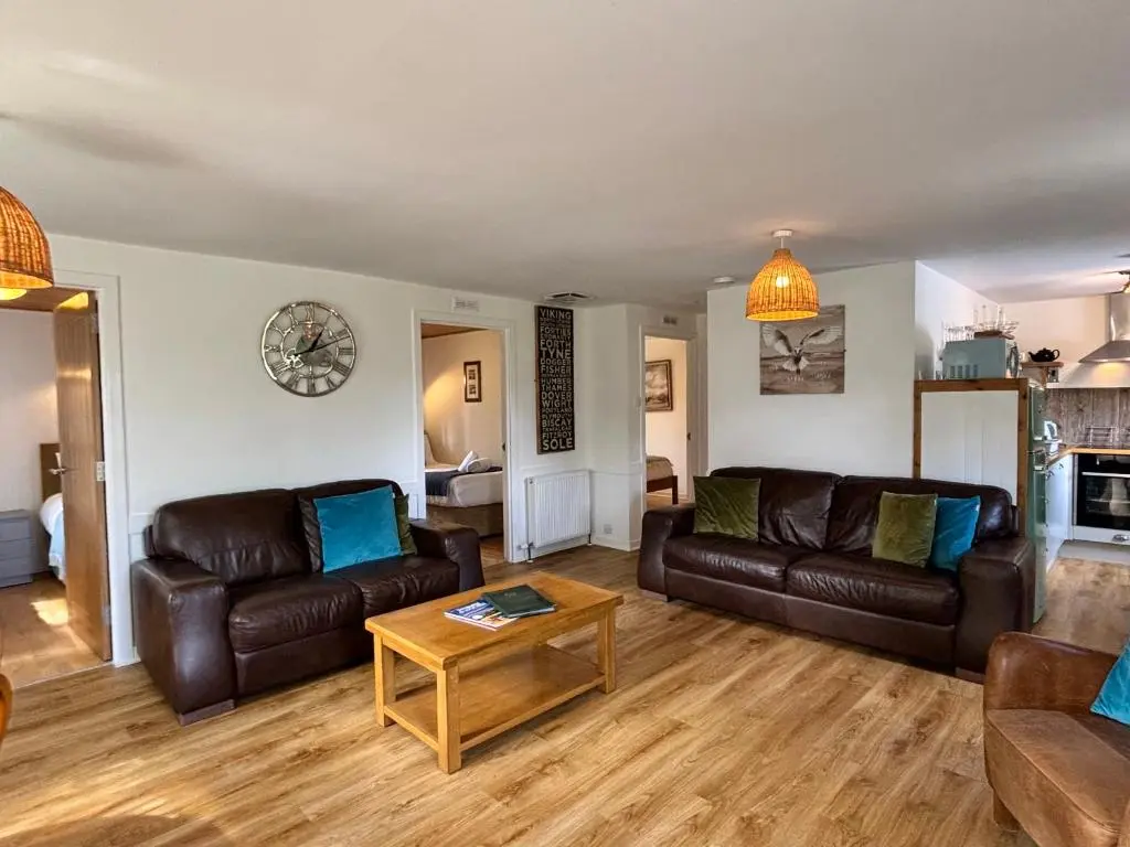 a living room with leather couches and a coffee table at Heather Lodge 17 with Hot Tub in Belladrum