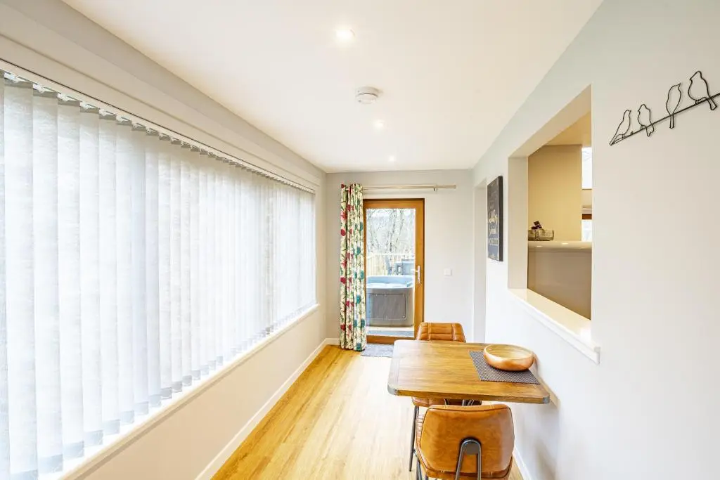 a dining room with a table and chairs and a window at Thistle Lodge 19 with Hot Tub in Belladrum