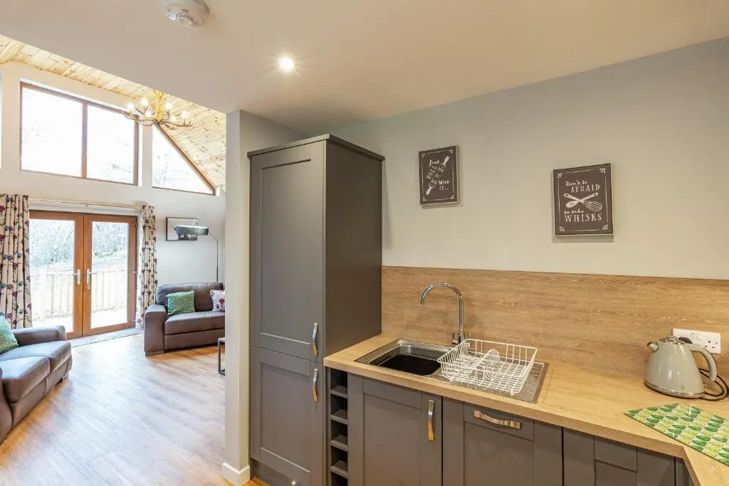 a kitchen with a sink and a living room at Thistle Lodge 19 with Hot Tub in Belladrum