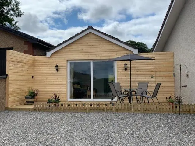 a patio with a table and chairs and an umbrella at TomaX Garden Cabin Free Parking in Inverness