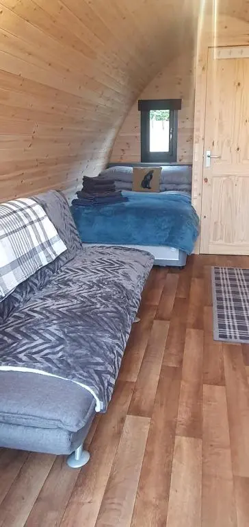 a bedroom with beds in a wooden cabin at The Pod at Hollingwell House - Glamping NC500 Edderton in Balblair