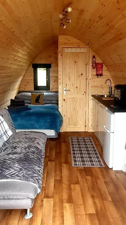 a bedroom with a bed in a wooden cabin at The Pod at Hollingwell House - Glamping NC500 Edderton in Balblair
