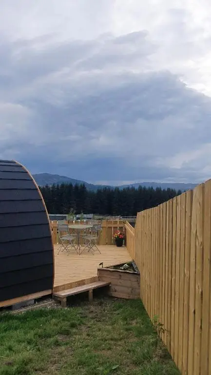 a wooden deck with a table and a fence at The Pod at Hollingwell House - Glamping NC500 Edderton in Balblair
