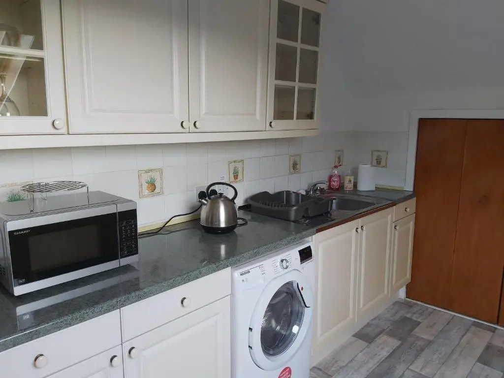 a kitchen with a washing machine and a microwave at Kirkhouse in Wick